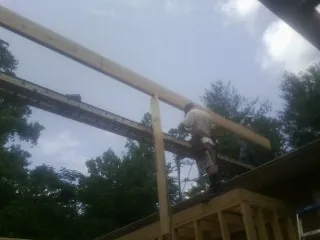 Carpenter setting a ridge beam over a new addition frame — Ice Dam Removal by Roofing Brothers in Dunsmuir