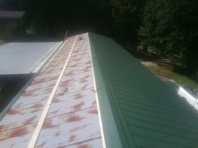Old rusted panels beside newly installed green metal roofing — Wind Damage Roof Repair by Roofing Brothers in Dunsmuir