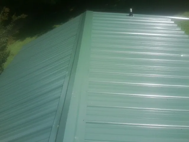 New green metal panels meeting at the ridge of a roof — Flat Roof Repair work by our crew in Dunsmuir