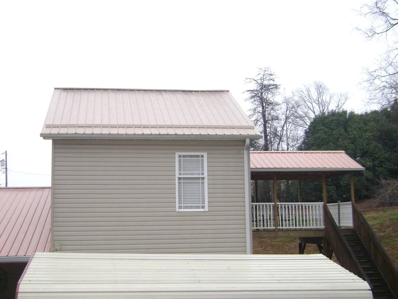 Tan metal roofs on a two story addition and attached porch, from a Roof Replacement job in Dunsmuir