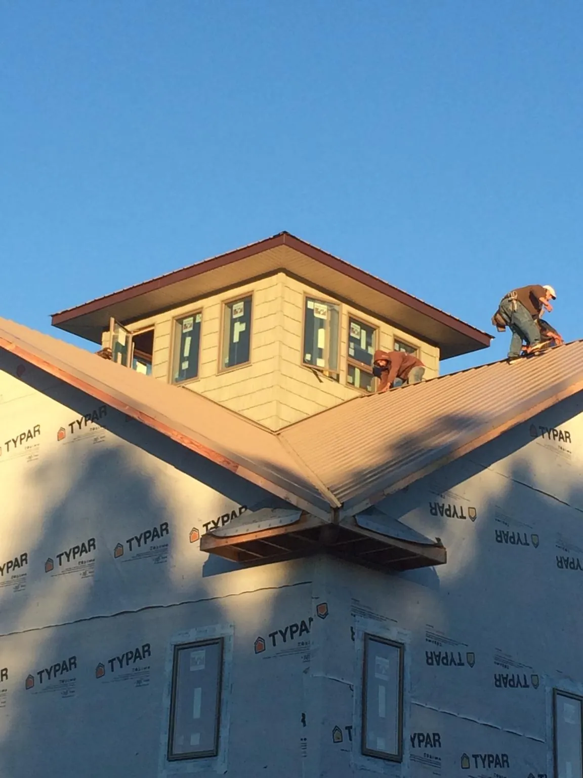 Roofers working around a rooftop cupola on a new metal roof at sunset — Roof Waterproofing in Dunsmuir by Roofing Brothers